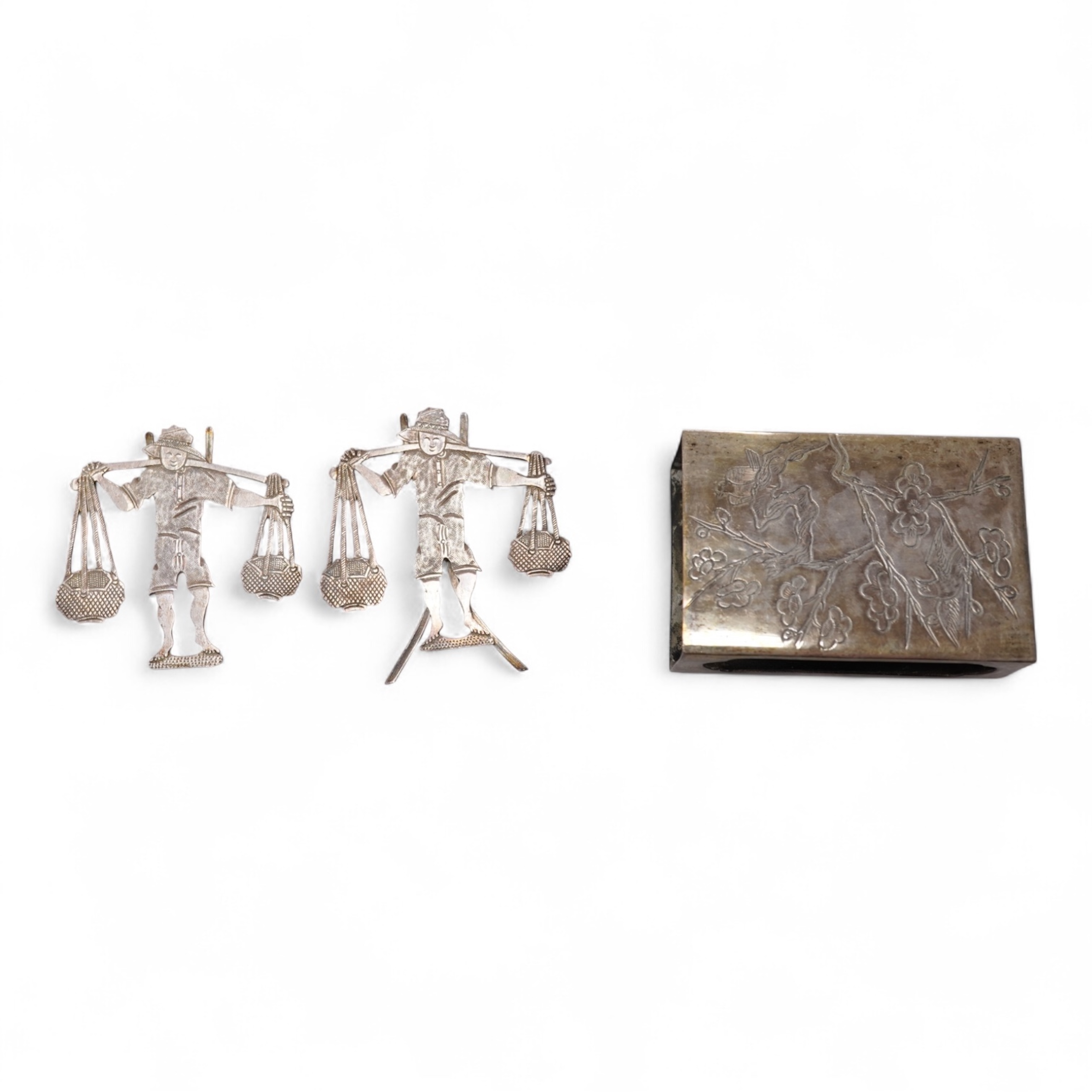 A Chinese Export white metal matchbox holder, with Chinese character mark stamp, embossed and engraved with dragon and prunus, 60mm and a pair of white metal figural menu holders, unmarked.